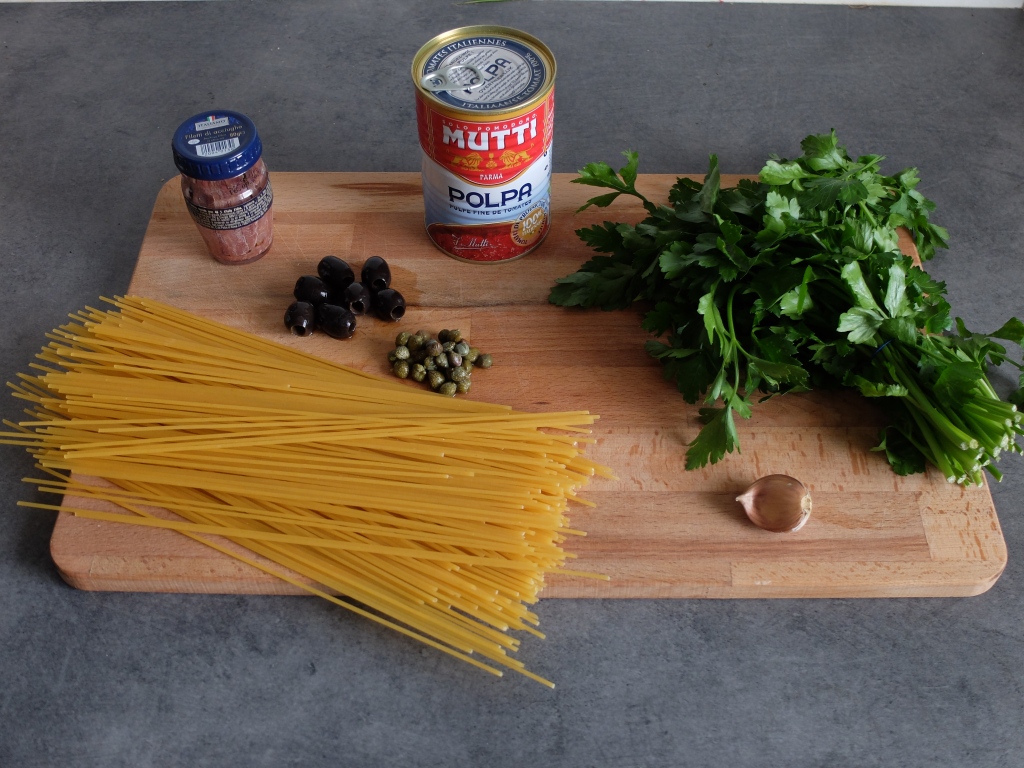 Les ingrédients nécessaires à la recette : pâtes, ail, olives noires, câpres, anchois, persil et huile d'olive. 